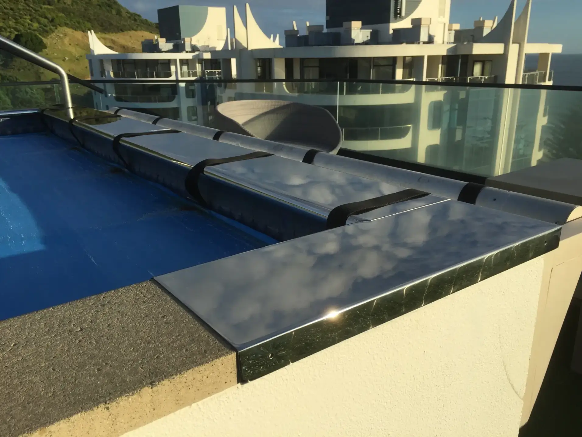 Stainless steel pool coping and glass balustrade